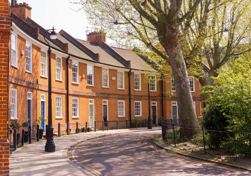Classic British crescent with restored Victorian red brick houses on a local road with small garden in front