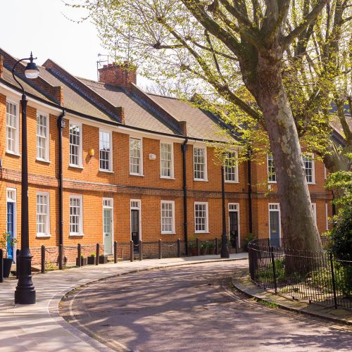 Classic British crescent with restored Victorian red brick houses on a local road with small garden in front